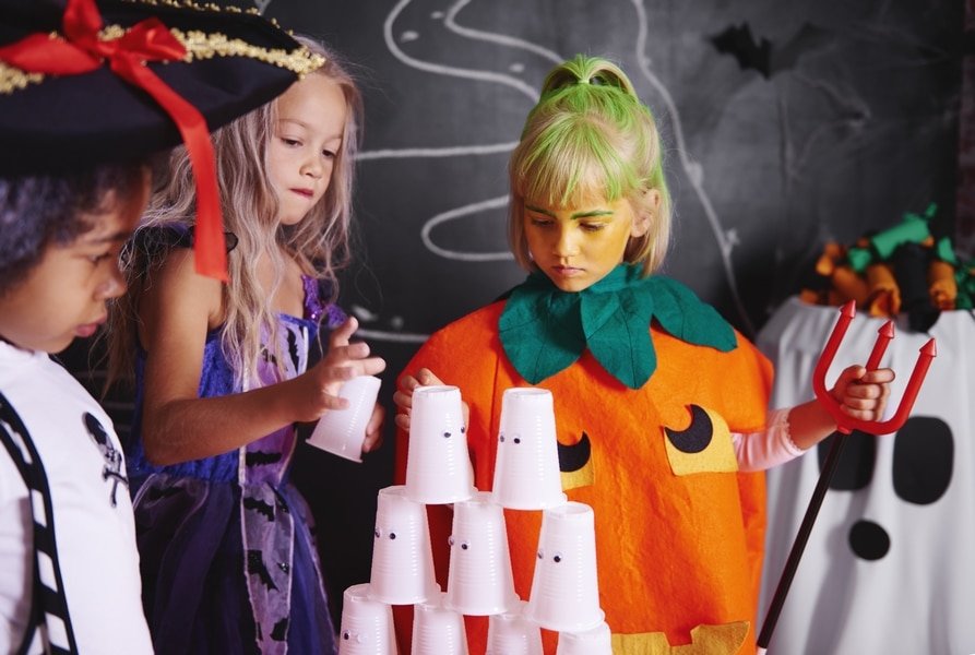 enfants déguisé pour Halloween qui construisent une pyramide de gobelets fantomes