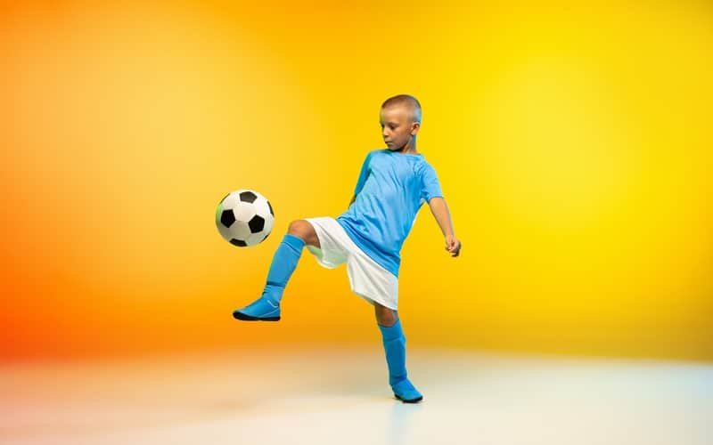 enfant en tenue d sport qui joue au foot