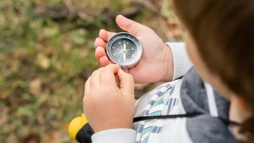 enfant tenant une boussole pour faire un jeu de piste