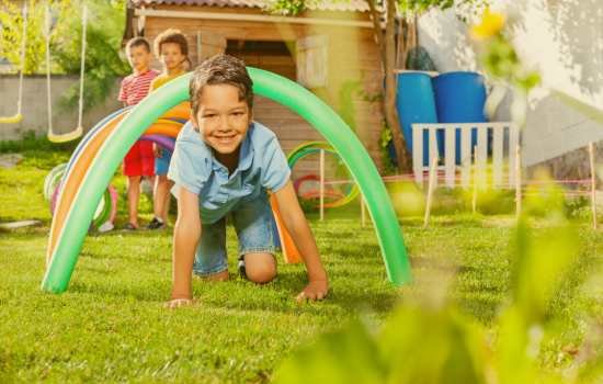 garçon qui passe sous un obstacle dans un jardin