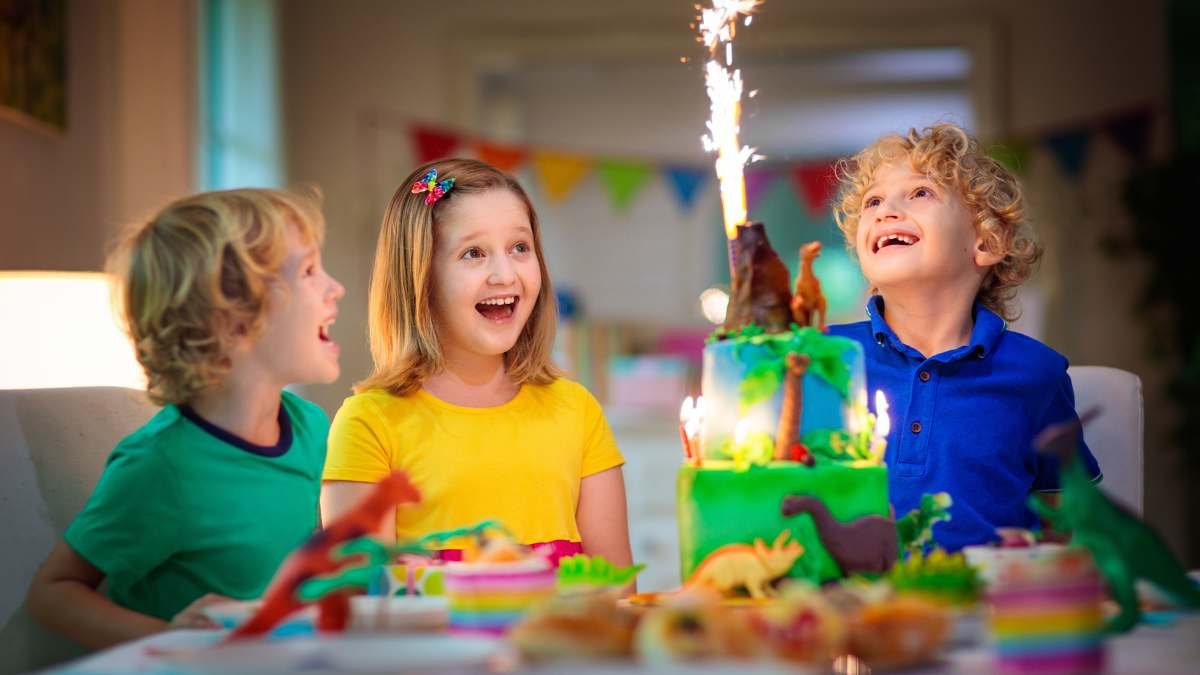 enfants qui regardent un volcan sur un gateau anniversaire dinosaure