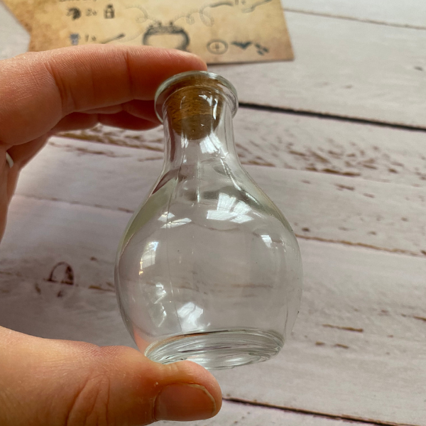 fiole de 8 cm de haut tenue entre le pouce et l'index